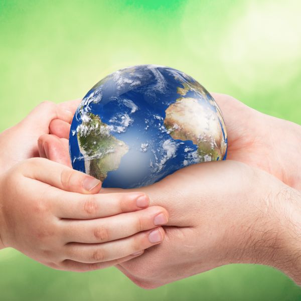 Father,And,Baby,Holding,Planet,In,Hands,Against,Green,Background.